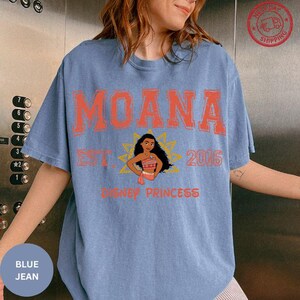 A woman wearing a blue t-shirt with the text "Moana" and "Disney Princess" printed on it.