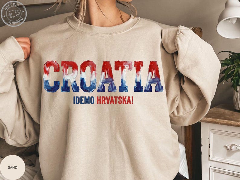A person wearing a beige sweater with the word "Croatia" printed on it in a stylized font.