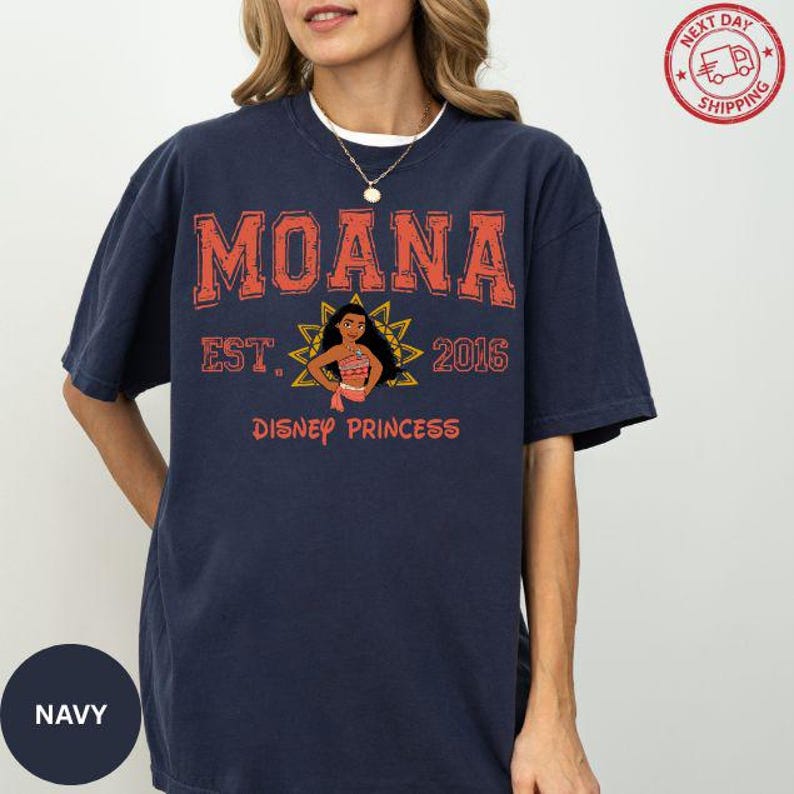 A woman wearing a navy blue t-shirt with the text "Moana Est. 2016 Disney Princess" printed on it.