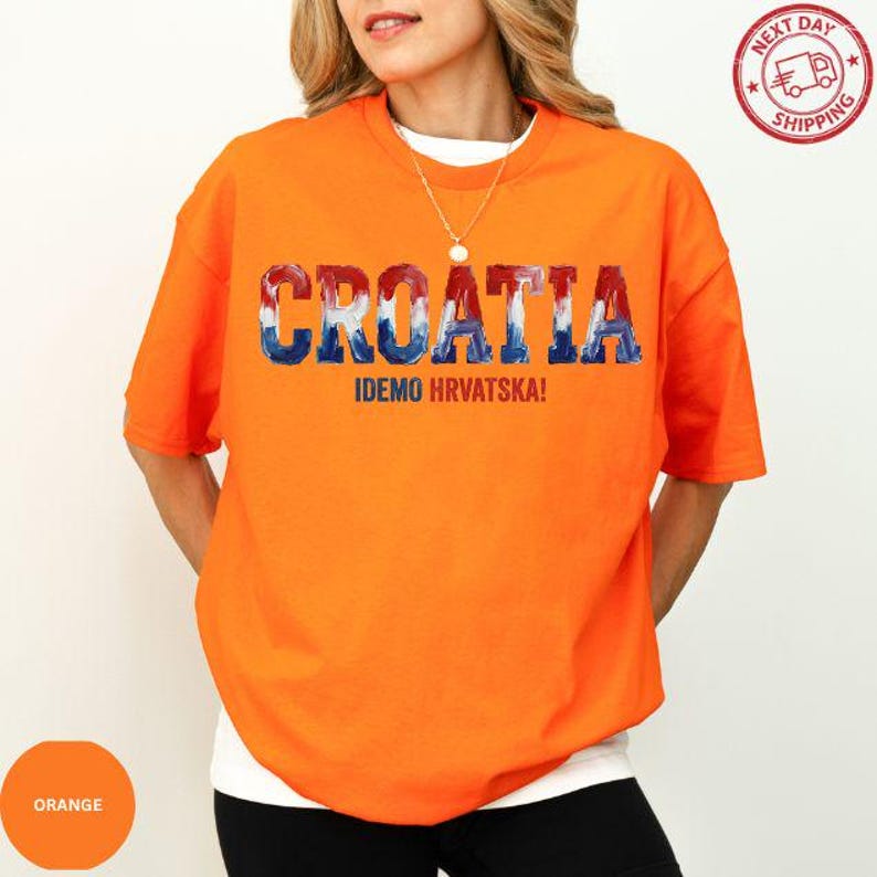 A woman wearing an orange t-shirt with the text "Croatia" and "IDEO HRVATSKA!" printed on it.