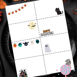 Puede incluir: Una hoja imprimible blanca con temática de Halloween con varias ilustraciones espeluznantes. Incluye un gato negro, una luna llena con murciélagos, una pancarta con fantasmas y calabazas, y el texto "Happy Halloween". El logotipo de DreamPop Printables es visible.