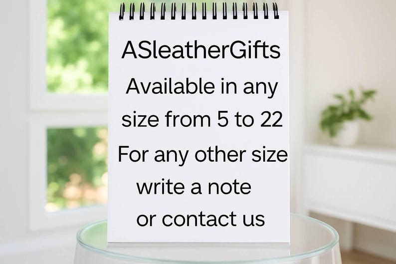 Puede incluir: Un bloc de notas blanco con encuadernaci&oacute;n en espiral y texto negro que dice: ASleatherGifts Available in any size from 5 to 22 For any other size write a note or contact us. El bloc est&aacute; colocado verticalmente sobre una superficie de cristal.