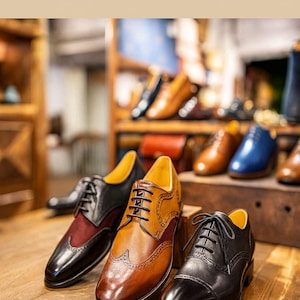 Puede incluir: Texto ASLeatherGifts sobre tres zapatos oxford de cuero. Un zapato es negro y burdeos, otro es color canela con detalles brogue y otro es negro s&oacute;lido. Cada zapato presenta cordones negros, punta redondeada y un forro interior amarillo.