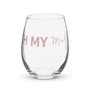 May include: A clear, stemless wine glass with the text "OH MY Mahj" in a soft pink script. The glass has a rounded shape and is designed for easy handling. Perfect for enjoying your favorite beverage.