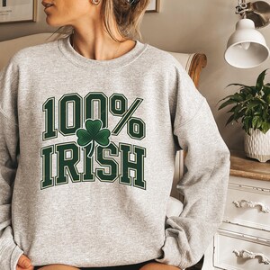 May include: A light gray sweatshirt with the text "100% Irish" in green block letters and a green shamrock. The sweatshirt is a crew neck style.
