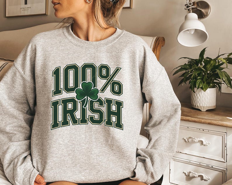 May include: A light gray sweatshirt with the text "100% Irish" in green block letters and a green shamrock. The sweatshirt is a crew neck style.