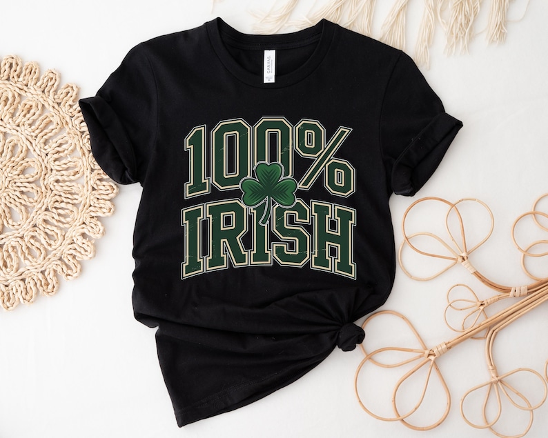 May include: Black t-shirt with the text "100% Irish" in green and white lettering, featuring a green shamrock. The shirt is folded and knotted at the bottom.