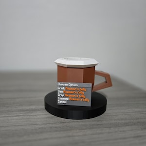 May include: A brown and white mug with a geometric design, featuring a handle and a black base. A small sign displays the text "Choose Option" and several options related to "Axeman's folly".