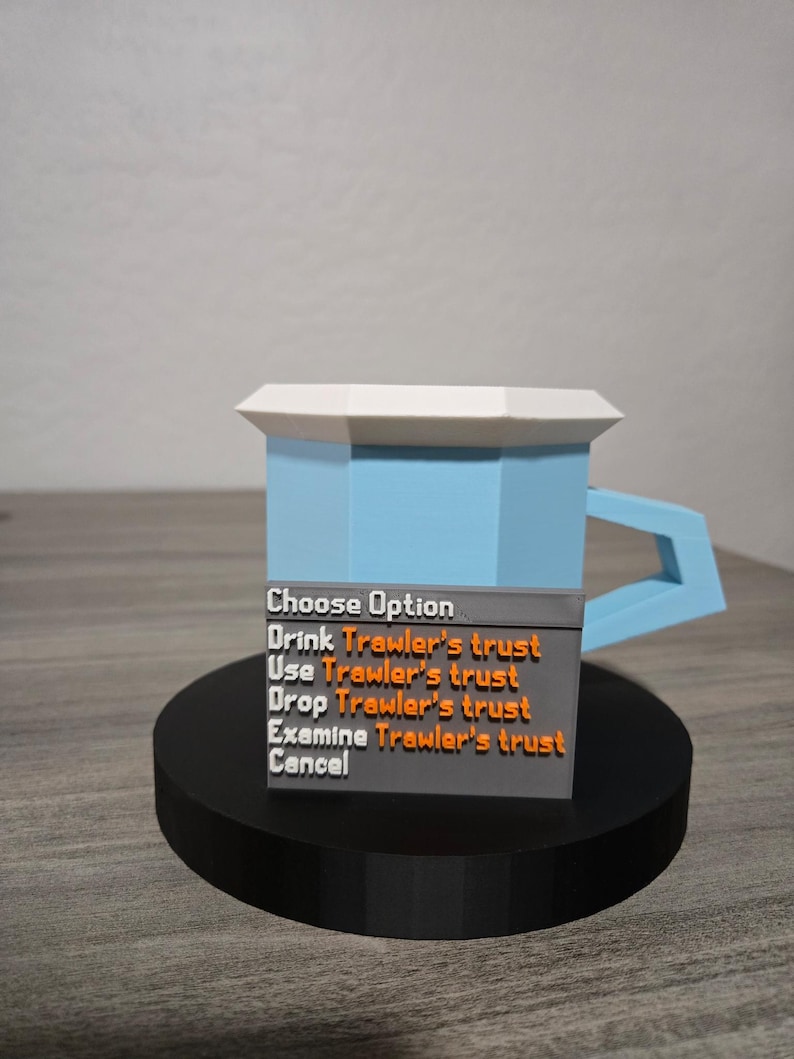 May include: A 3D-printed mug with a light blue body, white rim, and blue handle. The mug sits on a black circular base. A gray panel displays the text "Choose Option" and several action options in orange text.