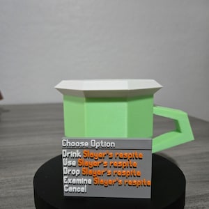 May include: A 3D-printed green mug with a white rim and handle, and a black base. A gray rectangular sign displays the text "Choose Option" and several options including "Drink Slayer's respite".