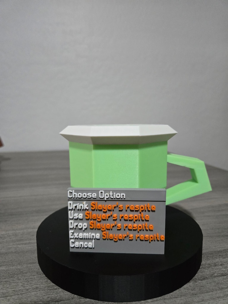 May include: A 3D-printed green mug with a white rim and handle, and a black base. A gray rectangular sign displays the text "Choose Option" and several options including "Drink Slayer's respite".