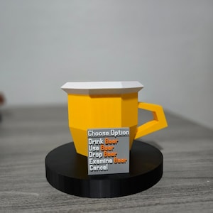 May include: A yellow polygonal beer mug with a white top and a handle, on a black circular base. A small grey rectangle displays the text "Choose Option" and beer-related actions. The mug is a 3D-printed item.