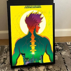 K&ouml;nnte beinhalten: Gerahmte Illustration eines Anime-Charakters mit leuchtenden Farben. Der Charakter hat rote Haare und einen gr&uuml;nen K&ouml;rper, vor einem gelben Hintergrund. Der Text oben lautet "CD PROJEKT RED X STUDIO TRIGGER CYBERPUNK: EDGERUNNERS."