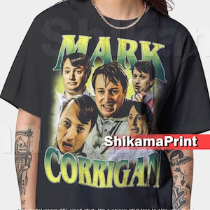 Peut inclure: T-shirt noir avec un graphisme de Mark Corrigan de la série britannique "Peep Show". Le design comprend plusieurs images du personnage avec le nom "MARK CORRIGAN" dans un style vintage. Le t-shirt est de style unisexe.