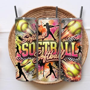 Può includere: Tre bicchieri cilindrici con cannucce nere a tema softball. Il design include palline da softball gialle, sagome nere di giocatori che colpiscono la palla e la parola Softball in lettere audaci e colorate su uno sfondo con schizzi.