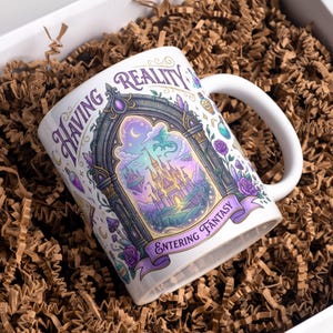 May include: White ceramic mug with a fantasy-themed design. The mug features a castle, dragon, and the words "Having Reality Entering Fantasy." Purple and green accents adorn the design, set against a white background. The mug is presented in a white box with brown packing material.