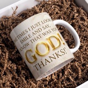 May include: White ceramic mug with a curved handle, featuring the words "SOMETIMES I JUST LOOK, SMILE AND SAY, I KNOW THAT WAS YOU, GOD! THANKS!" in gold and brown lettering. The mug is inside a white box with brown paper filler.