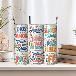 Pu&ograve; includere: Tre bicchieri cilindrici in metallo con cannucce, ciascuno caratterizzato da testi religiosi colorati e illustrazioni floreali. I design includono frasi come Dios es Amor, Amen, Jesus es el Pan de Vida, Amor Dios, Paz, Luz e Fe in vari caratteri.