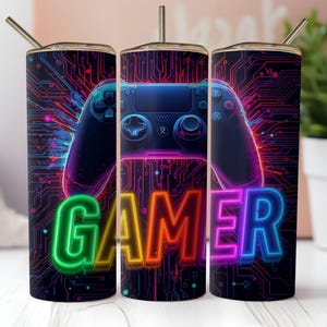 May include: A tall, insulated tumbler with a vibrant design featuring a neon-style video game controller and the word "GAMER" in colorful, glowing letters. The background has a circuit board pattern.