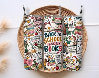 Puede incluir: Tres vasos cilíndricos de metal con pajitas negras, con un patrón colorido de gansos leyendo libros, útiles escolares y texto que incluye "Too Booked For Homework", "Back To School Back To Books" y "Library Goose On The Loose."