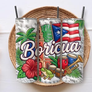 Può includere: Tre bicchieri isolanti bianchi con cannucce nere, ognuno con un design vibrante. Il design include la parola "Boriqua", una bandiera portoricana, un fiore di ibisco rosso e altri simboli culturali.
