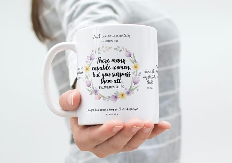 May include: White ceramic mug featuring a floral wreath design with the text "There many capable women, but you surpass them all." Additional text includes Bible verses. A perfect gift for any occasion.