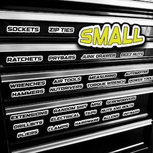 Puede incluir: Caja de herramientas negra con múltiples cajones etiquetados con categorías de herramientas. Las etiquetas incluyen "Sockets", "Zip Ties", "Ratchets", "Prybars", "Air Tools", "Wrenches", "Hammers", "Extensions", "Drillbits" y "Pliers". La palabra "SMALL" está en amarillo.
