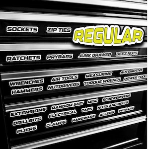 Op de afbeelding: Zwarte gereedschapskist met meerdere laden, elk gelabeld met witte tekst. Labels zijn onder meer "Sockets", "Zip Ties", "Ratchets", "Prybars" en "Junk Drawer". Een grote gele "REGULAR" sticker is zichtbaar.