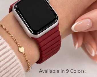 May include: A silver Apple Watch with a burgundy band is displayed on a wrist, paired with a gold bracelet. The watch band is ribbed. The image includes the text "Available in 9 Colors:" and a color palette of watch band options.