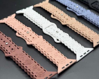 May include: A collection of watch bands in various colors, including white, pink, tan, and blue. Each band features a floral pattern and a scalloped edge. The bands are made of a flexible material.