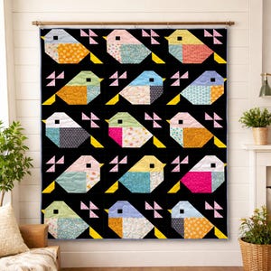 May include: A colorful quilt featuring a repeating pattern of geometric birds against a black background. Each bird is composed of various patterned fabrics in shades of blue, pink, orange, and yellow. The quilt is displayed on a wall.