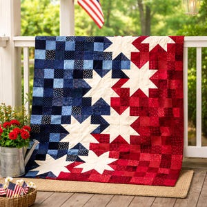 May include: A red, white, and blue quilt with a star design, draped over a white railing. The quilt's pattern features large white stars set against a backdrop of red and blue squares. The design evokes the American flag, suitable for a patriotic theme.