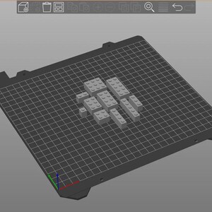 May include: A 3D rendering of gray toy building blocks arranged on a dark gray grid surface. The blocks are various rectangular shapes, suggesting a construction or design project. The background is a solid light gray.