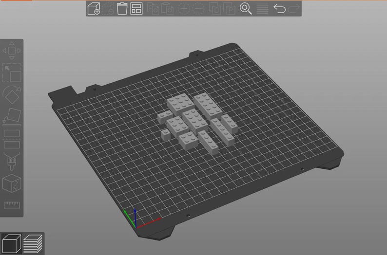 May include: A 3D rendering of gray toy building blocks arranged on a dark gray grid surface. The blocks are various rectangular shapes, suggesting a construction or design project. The background is a solid light gray.