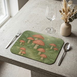 May include: A rectangular green placemat featuring a whimsical illustration of red and white spotted mushrooms amidst ferns. The placemat is designed for dining and adds a touch of nature-inspired decor to any table setting.