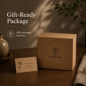 Puede incluir: Una caja cuadrada de cart&oacute;n marr&oacute;n con el logotipo de ZenBoodi y un s&iacute;mbolo circular con caracteres japoneses. Junto a la caja hay una peque&ntilde;a tarjeta rectangular marr&oacute;n con una ilustraci&oacute;n de bamb&uacute; y el texto Thank You Wishing you peace and happiness always.