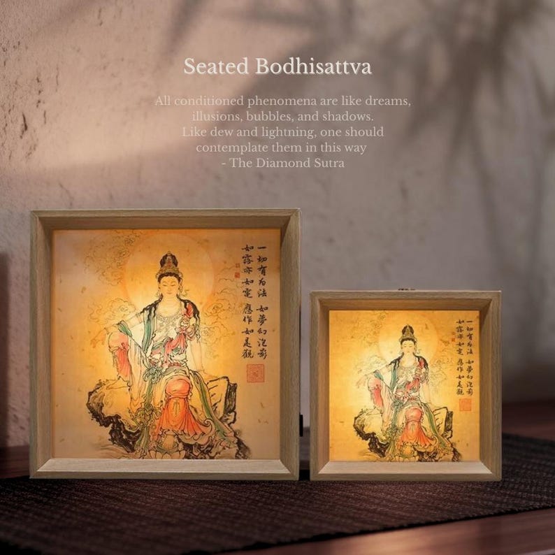 Puede incluir: Dos cajas de luz cuadradas con marco de madera clara que presentan una ilustraci&oacute;n de un Bodhisattva sentado. La obra muestra una figura con t&uacute;nicas, caligraf&iacute;a china y un sello rojo. El texto superior dice: Seated Bodhisattva. All conditioned phenomena are like dreams, illusions, bubbles, and shadows. Like dew and lightning, one should contemplate them in this way - The Diamond Sutra.