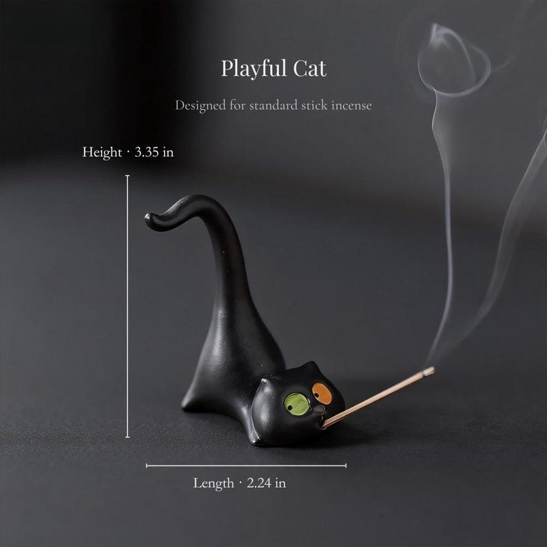 May include: A black cat-shaped incense holder with a green eye and an orange eye, holding a stick of incense. The text reads Playful Cat, Designed for standard stick incense, Height 3.35 in, Length 2.24 in. The cat has a long, curved tail.