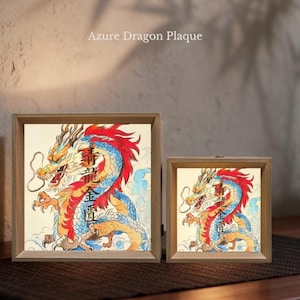 Puede incluir: Dos placas cuadradas de madera con una ilustraci&oacute;n de un drag&oacute;n con escamas azules, melena roja y detalles amarillos. La obra incluye caracteres chinos negros alineados verticalmente. El texto "Azure Dragon Plaque" aparece arriba.