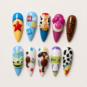 May include: Ten almond-shaped press-on nails featuring colorful 3D designs inspired by animated toys. The set includes motifs like a red star, blue toy blocks, cow print, a green three-eyed alien, a spring dog, a space ranger suit, and the name Andy.