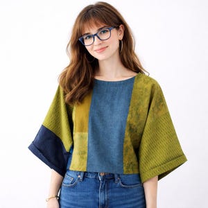 May include: A patchwork top with a round neckline and short sleeves. The top features panels of denim blue, olive green, and mustard yellow fabrics. The sleeves are cuffed, and the overall style is casual and modern.