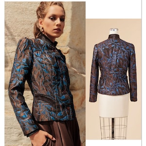 May include: Vogue Patterns sewing pattern featuring a jacket with a stand-up collar. The jacket is brown with blue leaf-like patterns. The model is wearing the jacket with brown pants. The pattern is designed and printed in the USA.