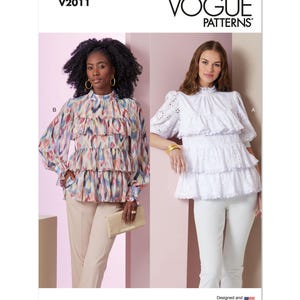 Könnte beinhalten: Vogue Patterns V2011. Das Bild zeigt zwei Blusen. Eine ist ein mehrfarbiges Oberteil mit Rüschen und langen Ärmeln. Die andere ist eine weiße, gestufte Lochbluse mit kurzen Ärmeln. Das Vogue Patterns-Logo befindet sich oben.