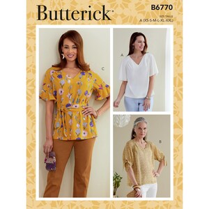 May include: A Butterick sewing pattern B6770 showing three V-neck top designs. The tops have short sleeves and tie details. The pattern includes sizes XS-XXL. The main image shows a yellow floral top with a tie.