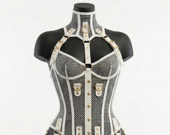 May include: A white mesh corset bodysuit featuring a high neck collar, gold-toned metal hardware, and adjustable straps with buckles. The garment includes integrated leg garter straps and a central vertical panel with gold studs, worn on a mannequin.