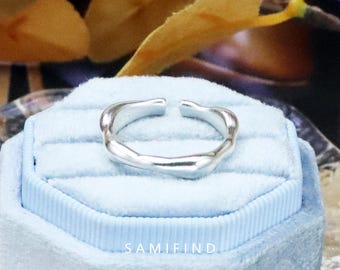 May include: A silver ring with an irregular, flowing shape, open at the front. The ring sits on a light blue velvet box. The image includes the text "SAMIFIND Handcrafted Jewellery" at the bottom.