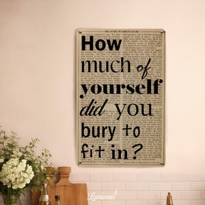 May include: A rectangular metal sign with the text "How much of yourself did you bury to fit in?" in a bold, black font. The background is a vintage newspaper print. The sign is displayed in a kitchen setting.