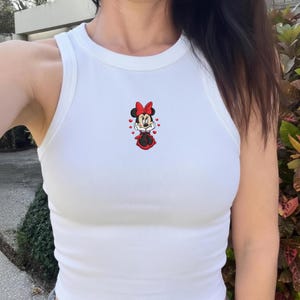 Peut inclure: Une tasse en c&eacute;ramique blanche avec une anse noire et le texte "But First, Coffee" en noir, dans une police manuscrite. La tasse est pos&eacute;e sur une surface blanche.