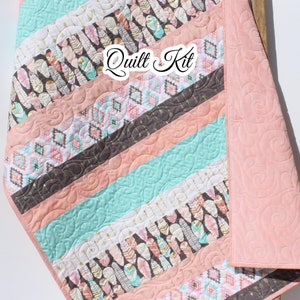 May include: A pink and turquoise quilt kit with a geometric pattern and a feather design. The kit includes fabric for the quilt top, backing, and binding. The quilt is perfect for a baby or toddler's room.