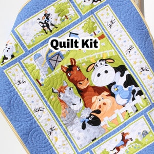 May include: A blue and green quilt kit featuring a farm animal theme. The kit includes a variety of fabrics with images of cows, horses, pigs, and sheep. The text "Quilt Kit" is printed on the fabric.